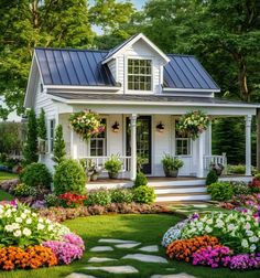 a white house surrounded by flowers and greenery