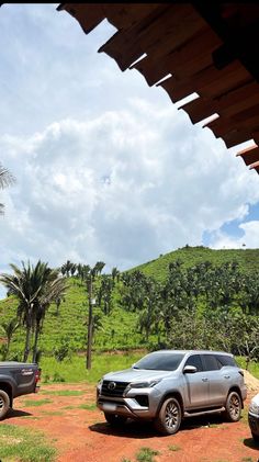 two suvs parked in front of a green hillside