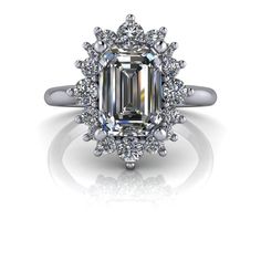 an emerald colored diamond surrounded by white diamonds in a halo setting on a silver ring