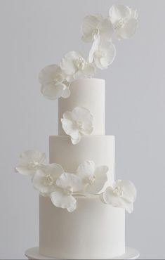 a three tiered white wedding cake with flowers on top