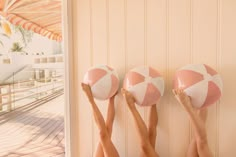 two women holding up pink and white beach balls