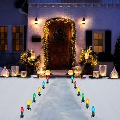 christmas lights are lit up in front of a house with snow on the ground and trees