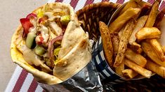 two baskets filled with food sitting on top of a table next to fries and coleslaw