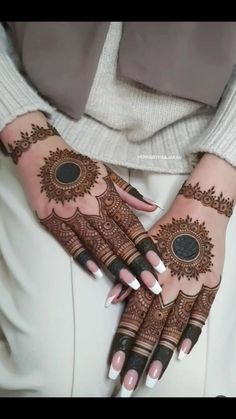 a woman's hands with henna tattoos on them