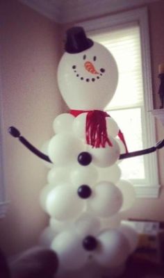 a snowman made out of balloons sitting on top of a table next to a window