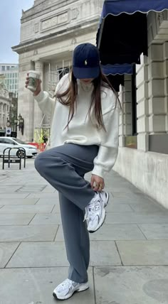 a woman sitting on the ground with an umbrella over her head and holding a coffee cup