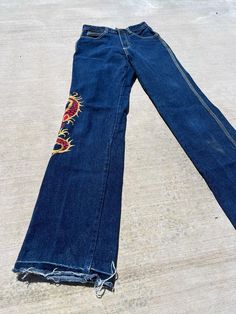 Stunning vintage Fredericks of Hollywood jeans from the 80s with super bold and graphic dragon embroidered on the left pant leg. They really don't make jeans like this anymore! The denim quality is superb with little to no stretch. Beautiful triple white top stitch down the side of the pant legs and ornate detailing on the back pockets with rivets to hold them in place. This pair of jeans had the length shortened at a time and then removed leaving a white band where the crease was and a raw hem 80s Pants Women, 80s Bottoms, Graphic Dragon, 80s Pants, Baddie Clothes, Visual Archive, Fredericks Of Hollywood, White Band, The 80s