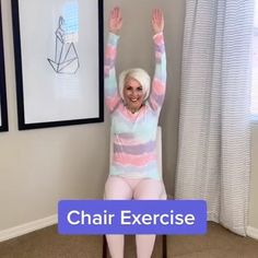 a woman sitting on top of a chair with her arms in the air