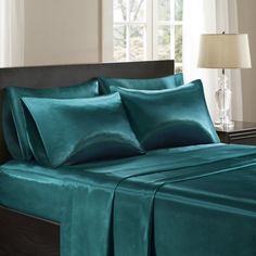 a bed with teal colored sheets and pillows