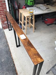 a wooden bench sitting on top of a cement floor next to a table and chairs