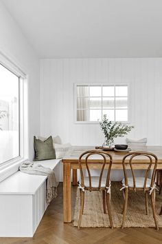 a dining room table with four chairs and a bench in front of the window,