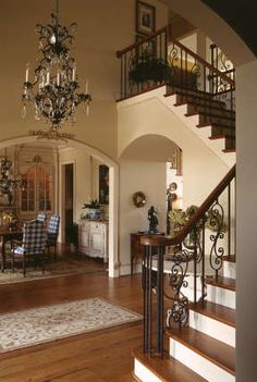 a large foyer with chandelier, table and chairs next to the stairs leading up to the second floor