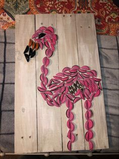 a piece of wood that has been painted with pink and black designs on it, sitting on a bed