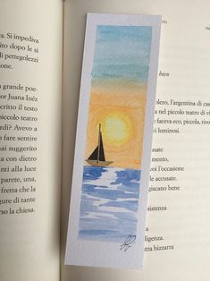 an open book with a watercolor painting of a sailboat in the ocean at sunset