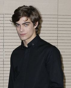 a young man standing in front of a wall