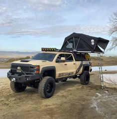 a pick up truck with an awning on the roof is parked near a body of water