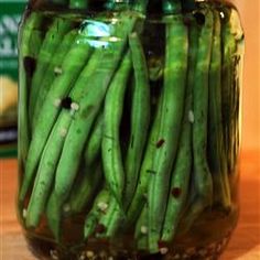 a jar filled with green beans sitting on top of a wooden table