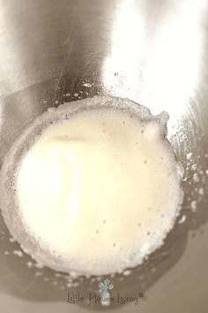 a metal bowl filled with white liquid on top of a table