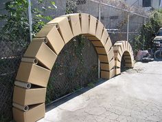 an arch made out of cardboard sitting next to a fence