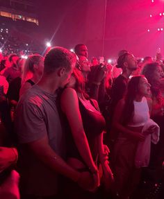 a group of people standing around in front of a crowd at a concert with bright lights