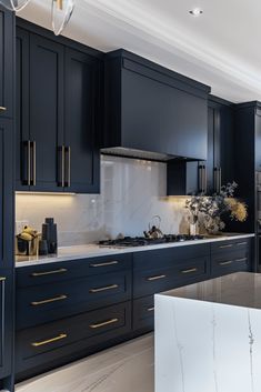 a large kitchen with black cabinets and marble counter tops, along with an island in the middle