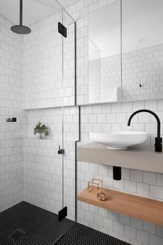 a bathroom with black and white tile, wooden shelfs and mirror on the wall