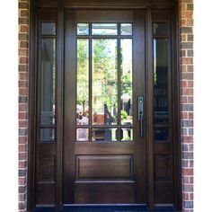 a wooden door with glass panels and sidelights on the outside of a brick building