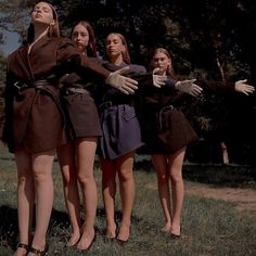 four young women in brown dresses are posing for the camera with their arms stretched out