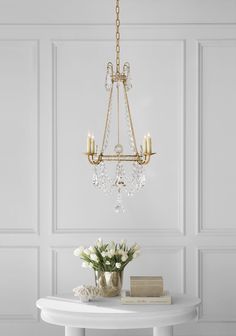 a chandelier hangs from the ceiling above a table with flowers and books on it