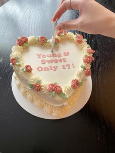 a heart shaped cake with the words young and sweet on it being cut by a knife