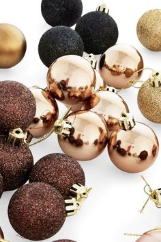 many different types of christmas ornaments on a white surface with gold, black and silver balls