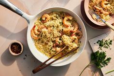 a bowl of shrimp and noodles with chopsticks next to it on a table