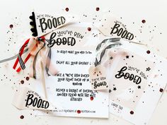 three pieces of white paper with black and red writing on them, tied together by ribbons