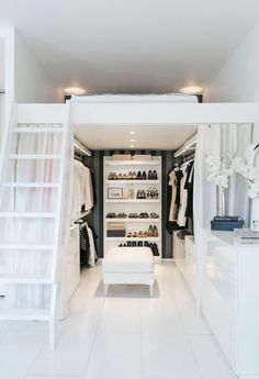 a white closet with shelves and shoes on the floor, in front of a window