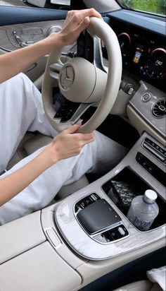 a woman driving a car with her hands on the steering wheel and holding onto the controls