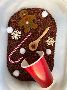 a white plate topped with chocolate cake covered in frosting and candy canes next to a red cup