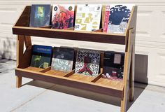 a wooden book stand with several books on it's sides, in front of a garage door