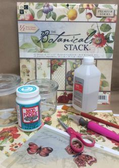 some crafting supplies are sitting on a table with flowers and butterflies in the background