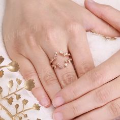 two hands holding each other with wedding rings on top of the fingers and gold leaves around them