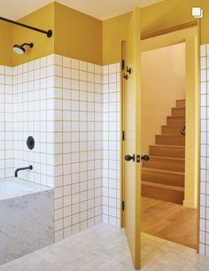 a bathroom with yellow walls and white tiles on the wall, along with a bathtub