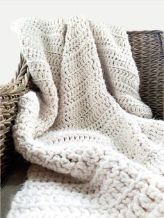 a white blanket sitting on top of a wicker basket