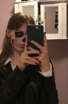 a woman with makeup on taking a selfie in front of her cell phone while wearing skeleton makeup