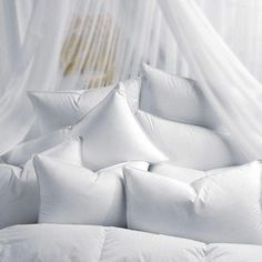 a bed with white sheets and pillows on top of it in front of a window