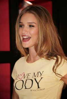 a woman with long hair smiling and wearing a t - shirt