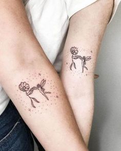 two people with matching tattoos on their arms, one holding the other's arm