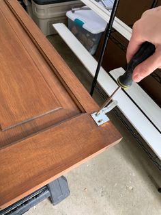 a person using a pair of scissors to trim a piece of wood on top of a table