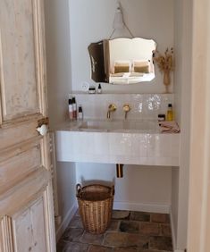 a bathroom sink sitting under a mirror next to a basket filled with soap and lotion