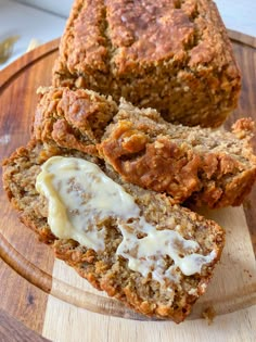 two slices of banana bread on a wooden plate with cream cheese spread over the top