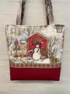 a red and white tote bag with a snowman in front of a barn