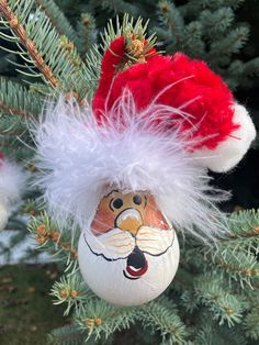 a christmas ornament with a santa hat on it hanging from a pine tree